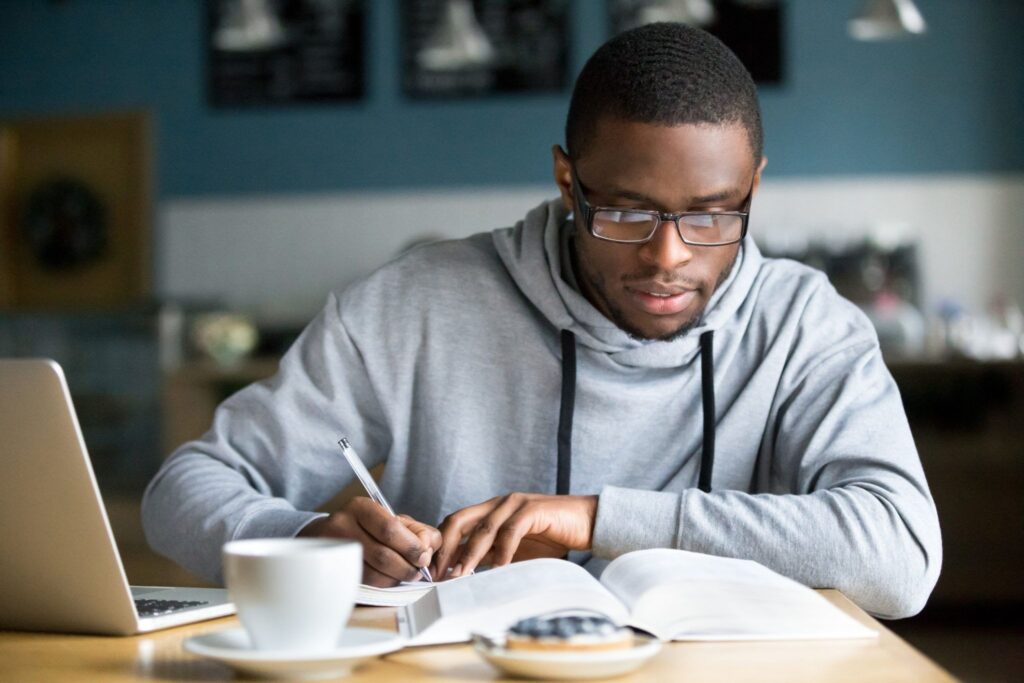 a person with pen in hand, scouring a book, doing research