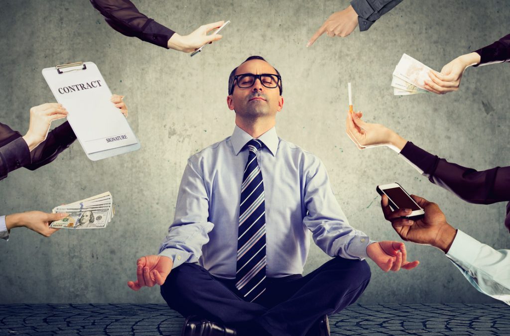 a man sitting in a yoga pose with hands offering challenges from each side