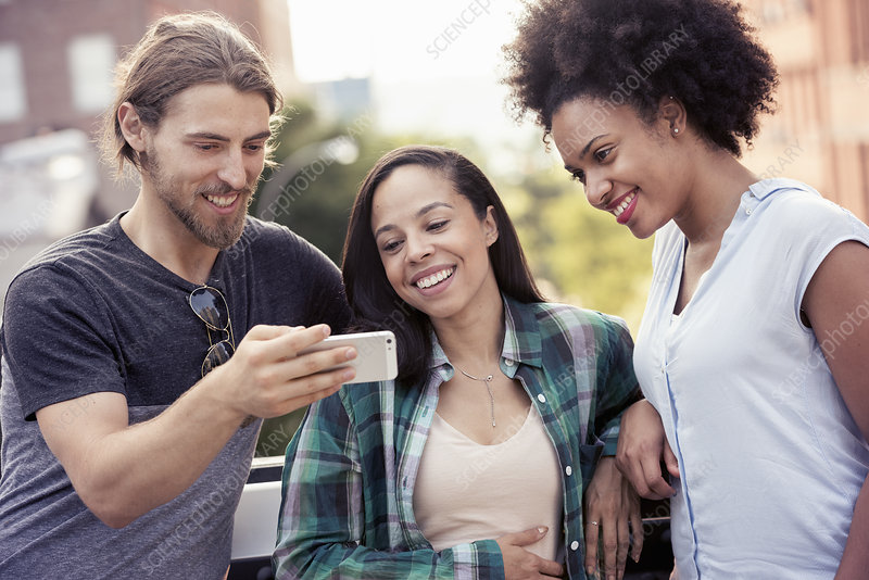 Three people looking at a smart phone